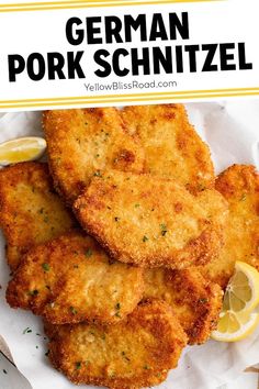 fried pork schnitz on a white plate with lemon wedges