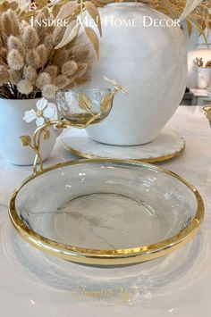 there is a white vase with gold trim around it and two plates on the table