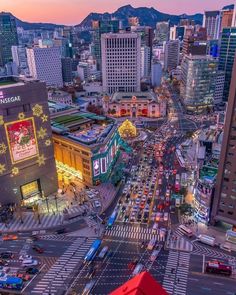 an aerial view of a busy city street at dusk with mountains in the back ground