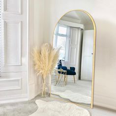 a mirror in the corner of a room next to a table with a vase on it