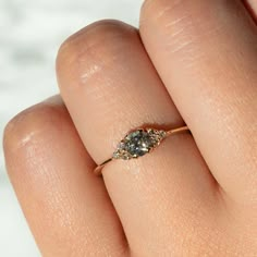 a woman's hand with a diamond ring on top of her finger and the other hand holding an engagement ring