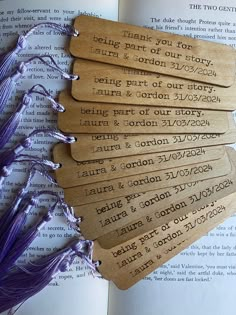 five wooden tags with names on them sitting on top of an open book next to some lavender flowers