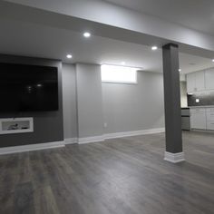 an empty living room with wood floors and white cabinets in the backround is a flat screen tv