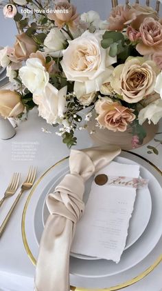 the table is set with white plates, silverware and pink flowers in vases