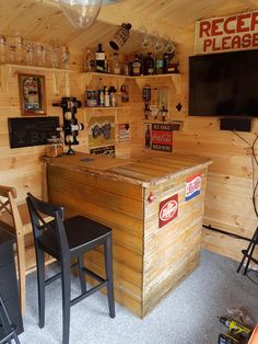 a small bar in the corner of a room with two chairs and a television mounted to the wall