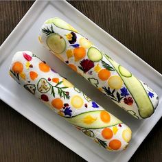 two slices of cucumber on a plate with flowers and leaves painted on them