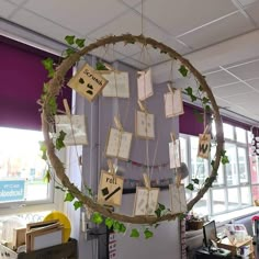 a circular hanging decoration with cards attached to it's sides and ivy growing on the side