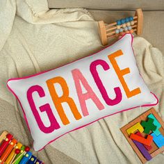 a pillow with the word grace on it next to crayons and wooden toys