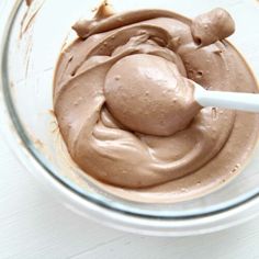 a glass bowl filled with chocolate frosting on top of a white table