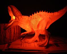 a lit up dinosaur figurine sitting on top of a piece of paper