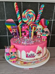 the birthday cake is decorated with lol surprisers, candy and lollipops