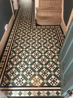 a hallway with green and white tiles on the floor, stairs and handrails