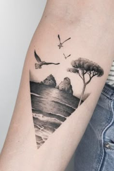 a woman's arm with a bird flying over the water and trees on it