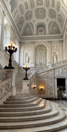 an ornate staircase in a building with chandeliers and marble steps leading up to the second floor