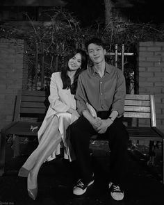 black and white photograph of two people sitting on a bench