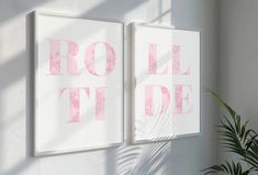 two pink and white posters on the wall next to a potted palm tree in front of it