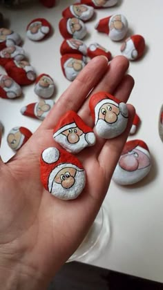 a hand holding some rocks with santa clause on them