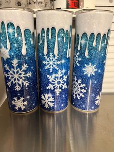 three blue and white cups with snowflakes on them sitting on top of a counter