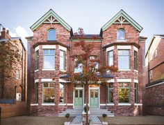 a large brick building with two story windows and green trim on the front door is shown