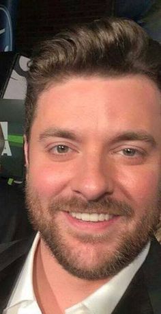 a man with a goatee and beard smiling at the camera while wearing a suit