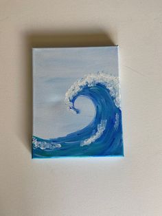 an acrylic painting of a blue wave on a white wall with the ocean in the background