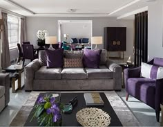 a living room with couches, chairs and tables in purple and grey colors on the walls