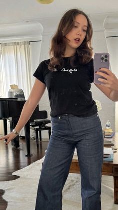 a woman standing in a living room holding a cell phone