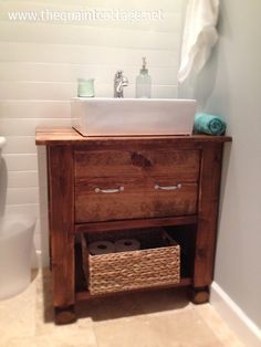 a bathroom with a toilet, sink and wooden cabinet in the shower stall is shown