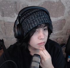 a person with headphones on sitting in front of a microphone and wearing a hat