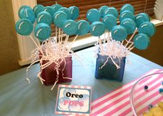 a table topped with blue and pink desserts next to cupcakes on top of cake pops