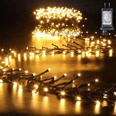 a string of christmas lights on a black surface with an image of a tree in the background