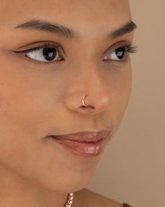 a close up of a woman wearing a necklace and nose ring with pearls on it