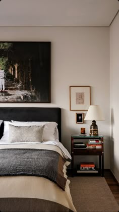 a bedroom with a bed, nightstand and pictures on the wall