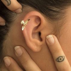 a close up of a person with tattoos on their ear and behind the ear an eye