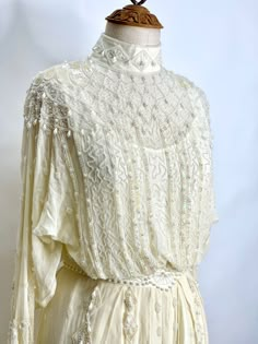 an antique white dress with beading on it