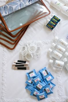 the contents of a travel bag laid out on top of a white tablecloth with blue ribbon