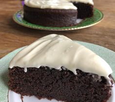 two slices of chocolate cake with white frosting on green plates next to each other