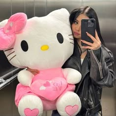 a woman taking a selfie with her hello kitty stuffed animal