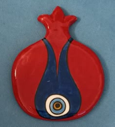 a red and blue vase with an evil eye on the bottom is sitting on a blue surface