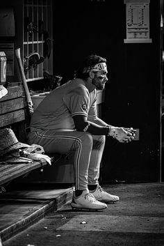 black and white photograph of a baseball player sitting on a bench with his glove in hand