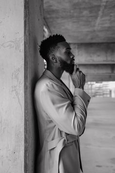 a man in a suit leaning against a wall