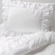 a white bed with ruffled sheets and pillows