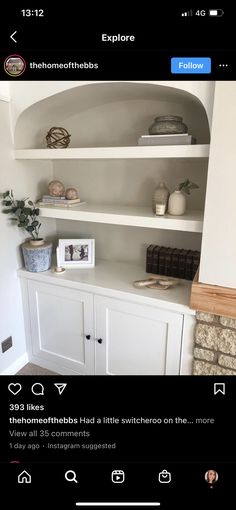 a white bookcase with shelves and pictures on the top, in front of a fireplace