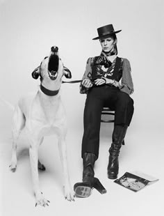 a man sitting on a bench next to a dog wearing a top hat and boots