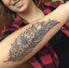 a woman with a flower and feather tattoo on her arm