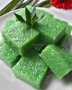 pieces of green jello on a white plate with a sprig of leaves