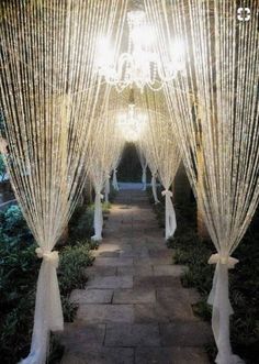 an outdoor wedding ceremony with white drapes and chandelier hanging from the ceiling