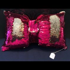 a pink and gold sequin pillow with a tag on it