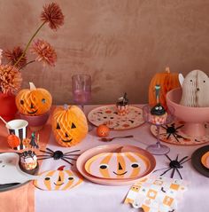 a table set for halloween with pumpkins and decorations