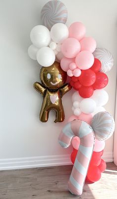 a balloon decoration with a teddy bear and candy canes on the wall next to it